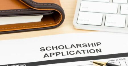 Printed scholarship application form with keyboard and pen